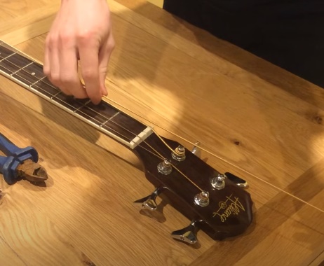 Insert acoustic bass strings in the tuning pegs
