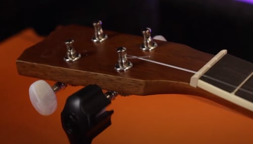 Insert the string in the tuning pegs and use the guitar winder