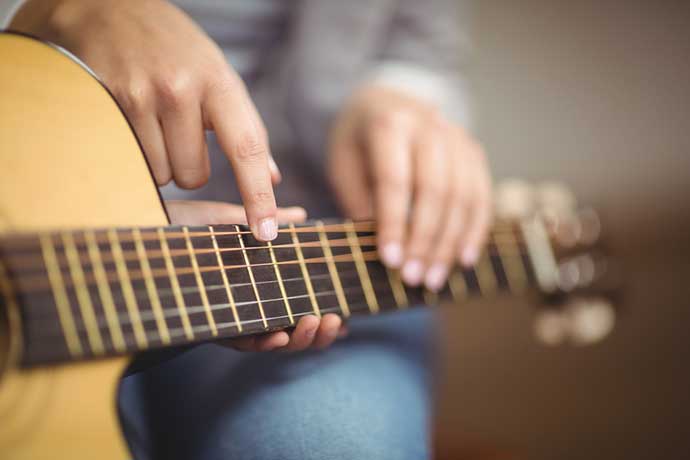 Teacher-giving-guitar-lessons-to-pupil-in-a-classroom